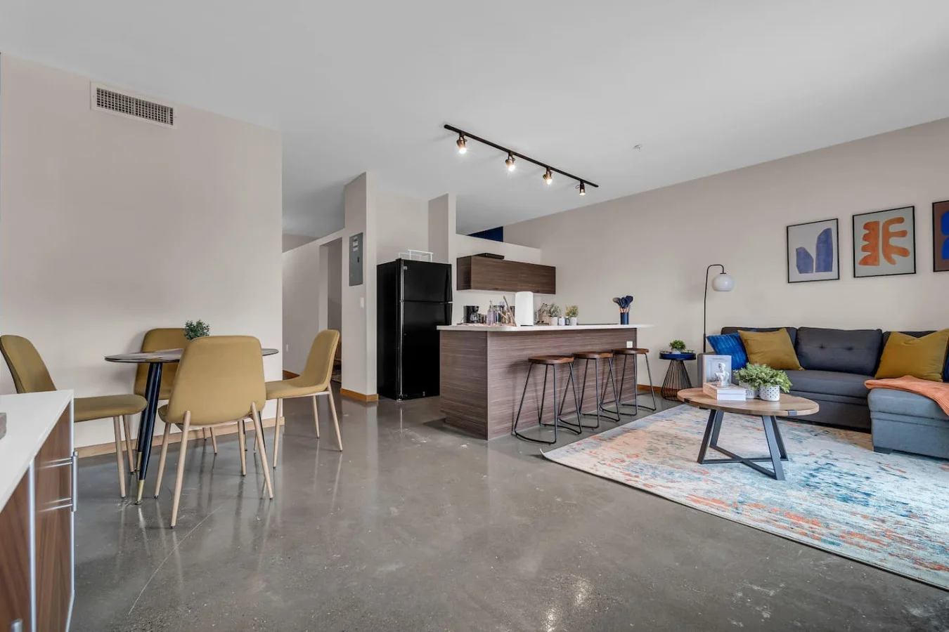 Spacious open-concept living and dining area featuring a vibrant blue sofa, modern furnishings, and a stylish entertainment setup—ideal for gatherings and relaxation.