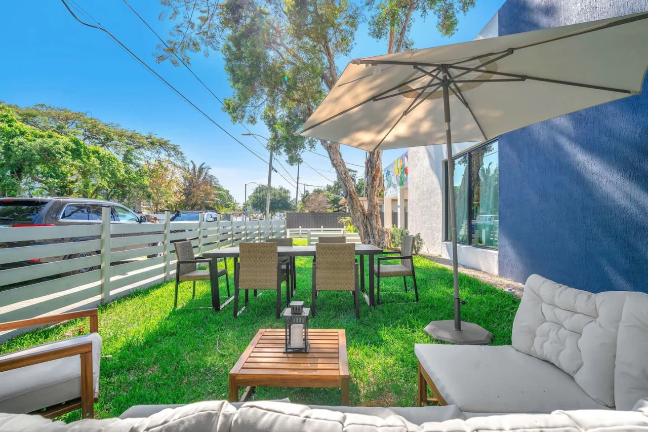 Modern outdoor seating, umbrellas, and a natural canopy of trees.