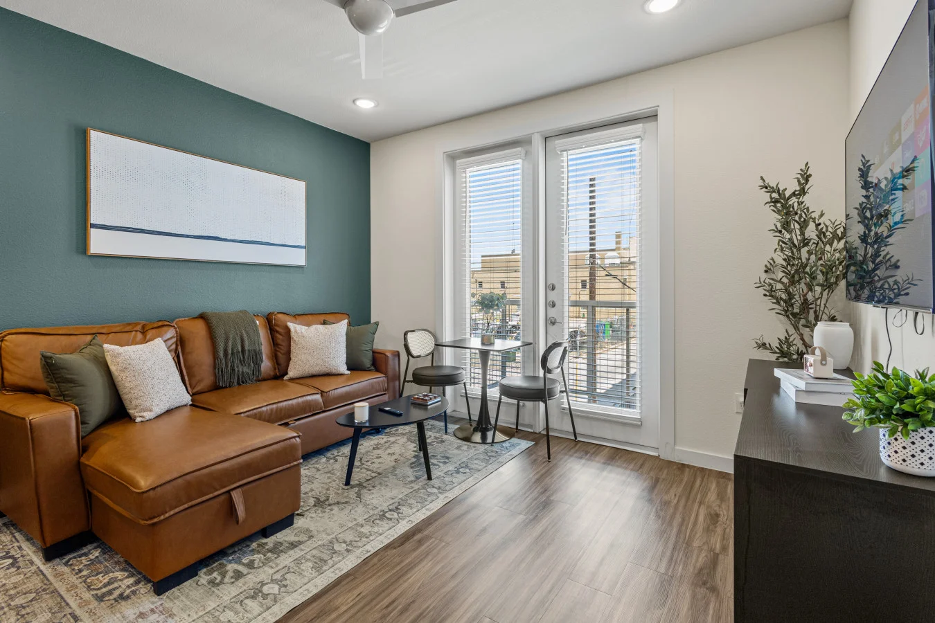 Relax in the stylish living room featuring a cozy leather sectional, vibrant green accent wall, and access to a private balcony.