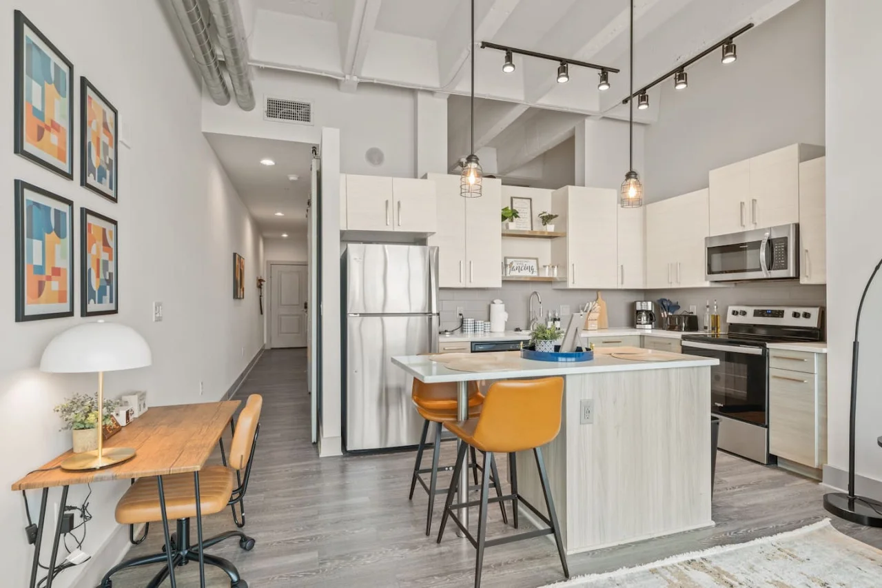 Prepare meals in this modern, fully-equipped kitchen featuring stainless steel appliances and a spacious island with bar seating. The open layout makes it easy to cook and entertain, ensuring a delightful culinary experience during your stay.