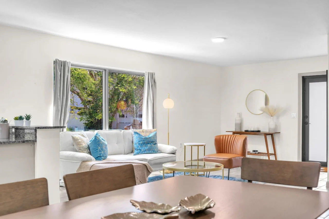 Elegant living area featuring a white sofa with bright blue and metallic accent pillows, paired with a glass coffee table.