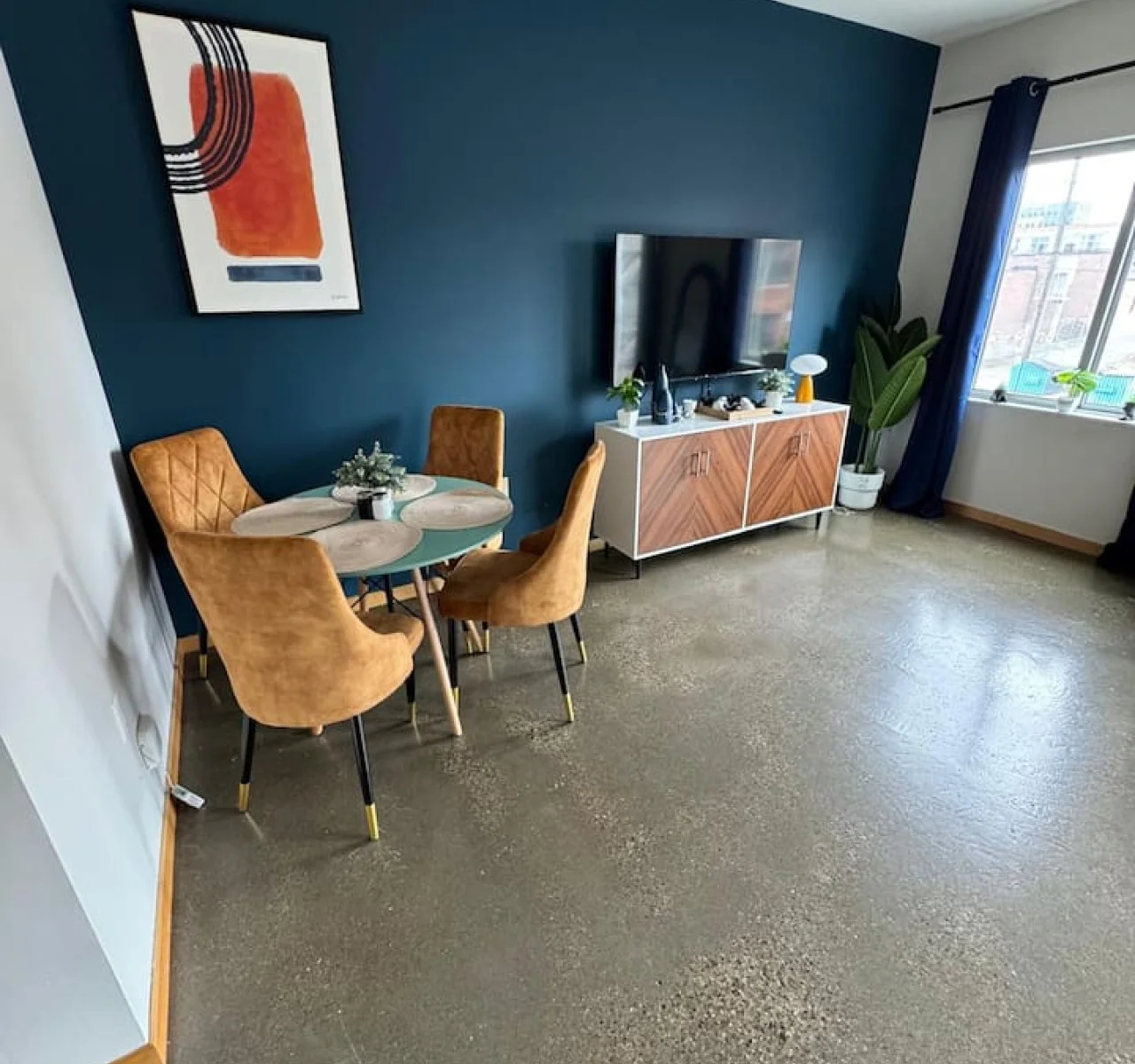 Spacious open-concept living and dining area featuring a vibrant sofa, modern furnishings, and a stylish entertainment setup—ideal for gatherings and relaxation.