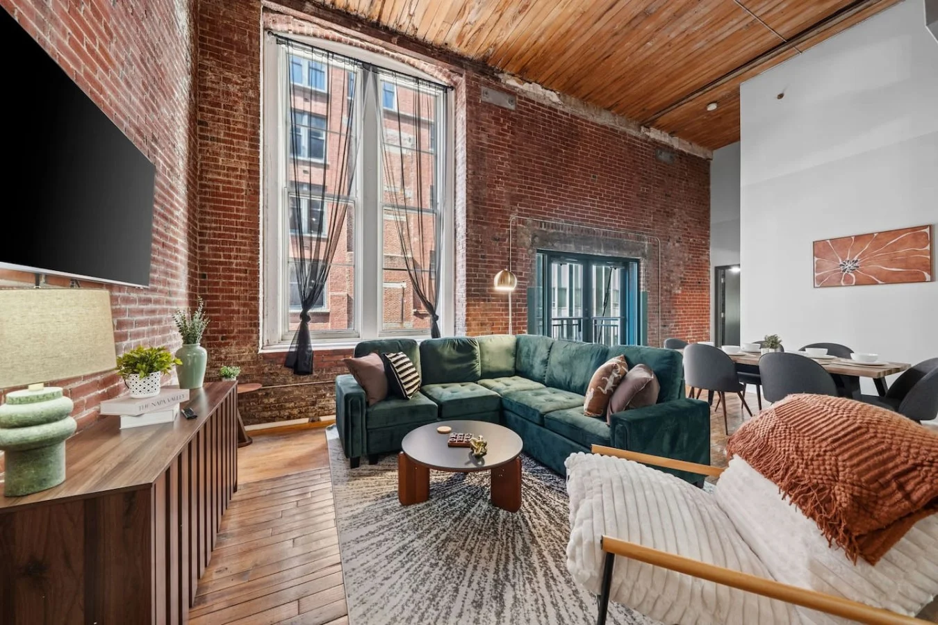 Cozy, stylish living room with modern décor, a comfy sofa, workspace, and natural light. Inviting mix of industrial and contemporary design perfect for relaxing or working.