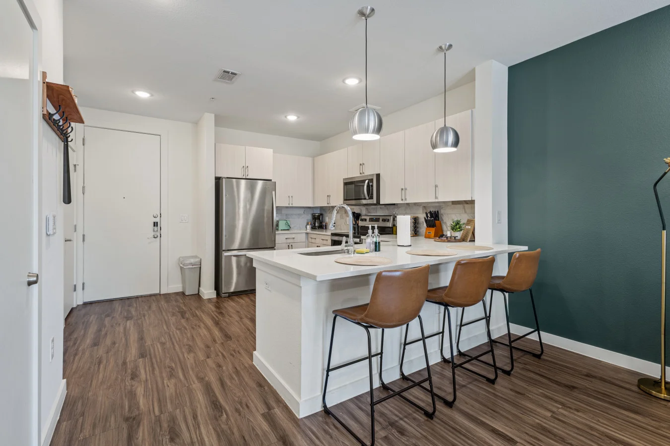 Sleek, modern kitchen featuring white cabinetry, stainless steel appliances, and a spacious island with seating—perfect for gathering and meal prep.