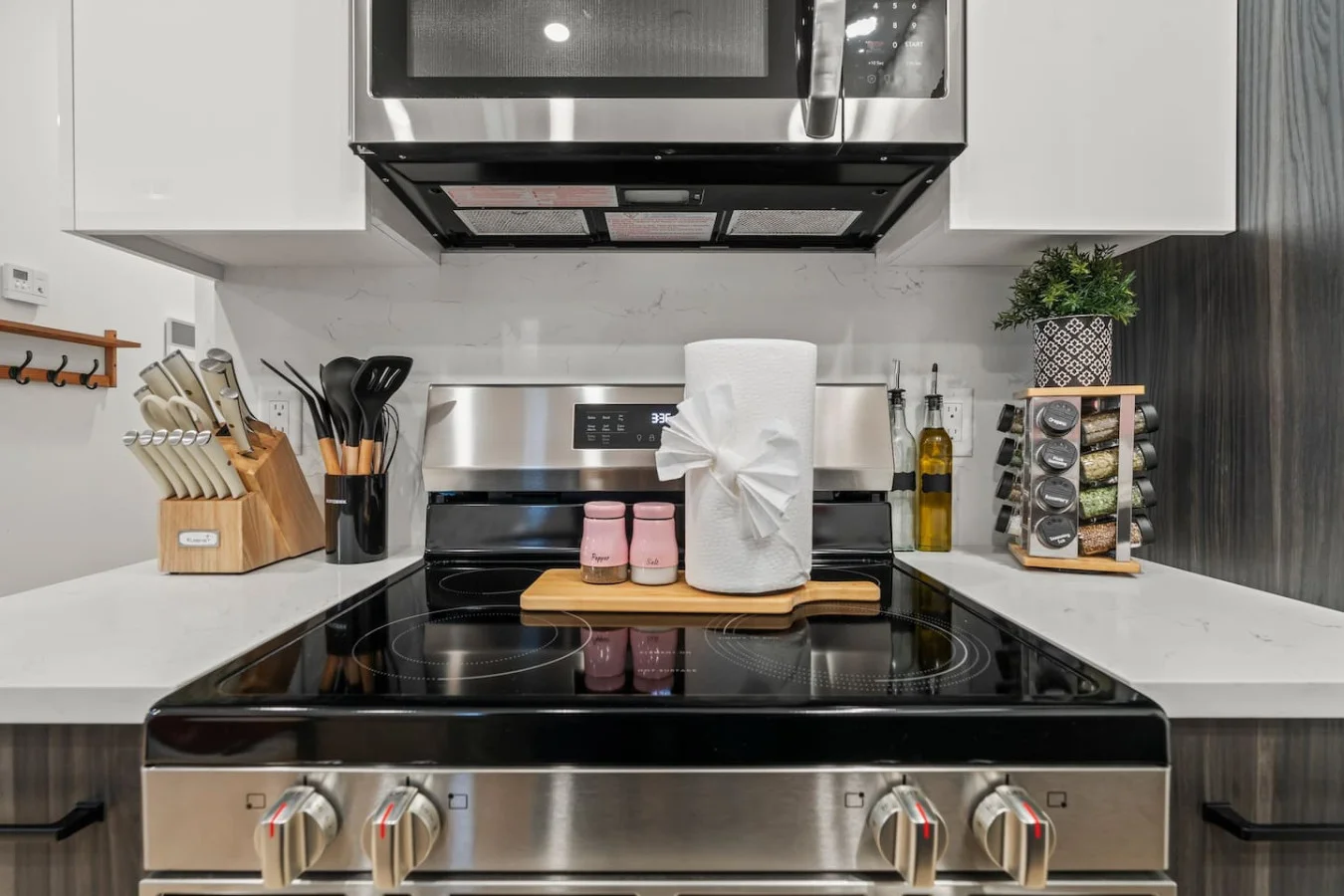 This modern kitchen features a spacious island with bold blue cabinetry, sleek white countertops, stainless steel appliances, open shelving, and stylish lighting.