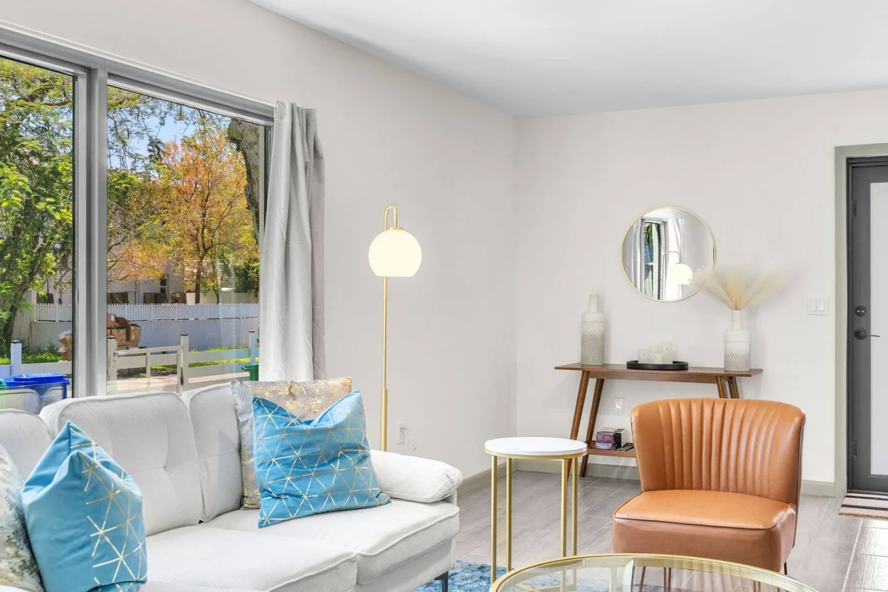 White sofa with a caramel accent chair and glass coffee table.