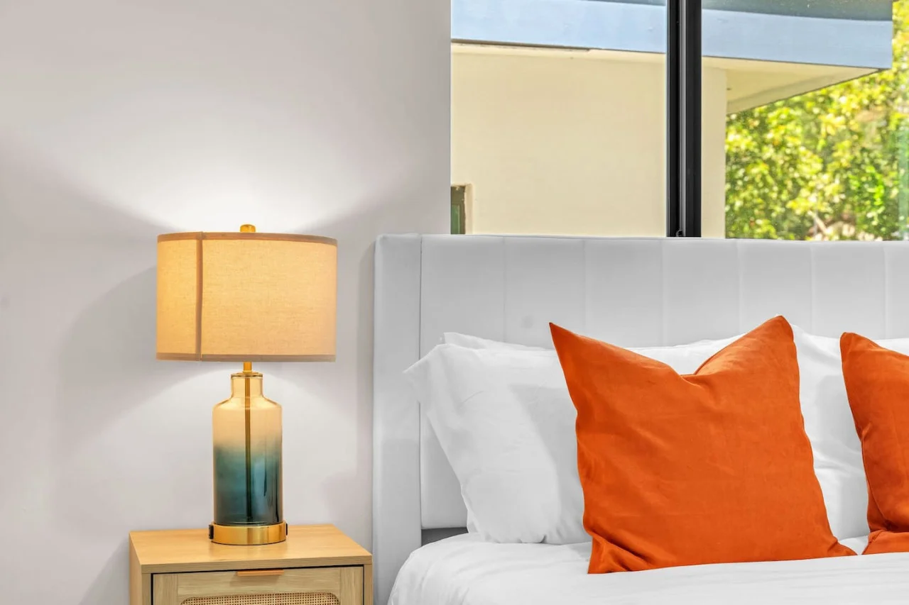Stylish lamps, paired with the bold orange pillows that add a pop of color to the room.