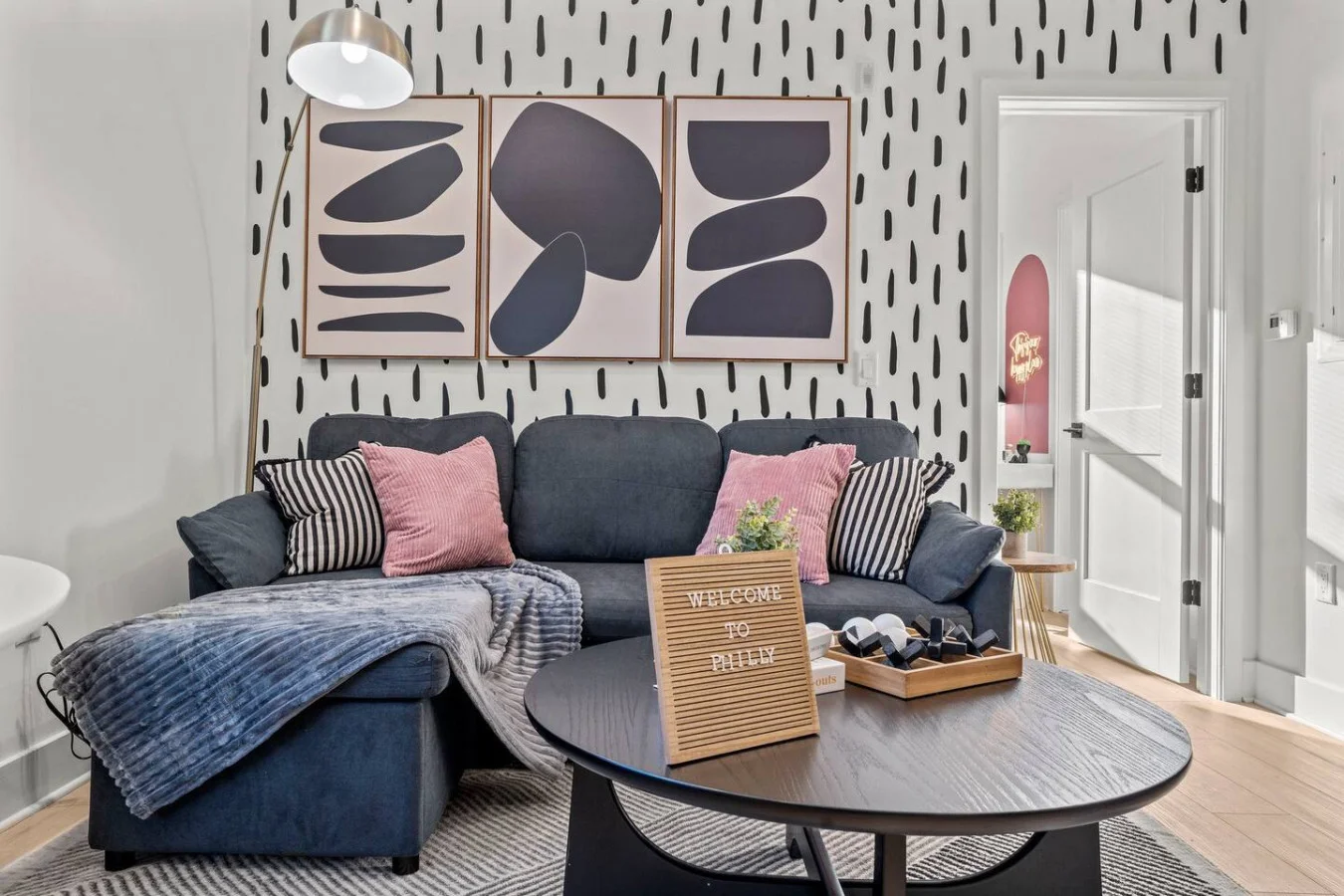Chic living space with a bold red sofa, modern art, and cozy touches for a warm Philly welcome.