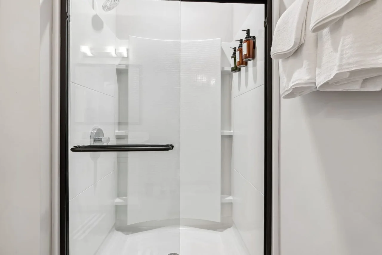 This bright and welcoming bathroom invites you to freshen up in comfort. Enjoy the forest-inspired shower curtain that adds a calming touch to your routine, complemented by the cozy rug underfoot and sparkling clean fixtures.