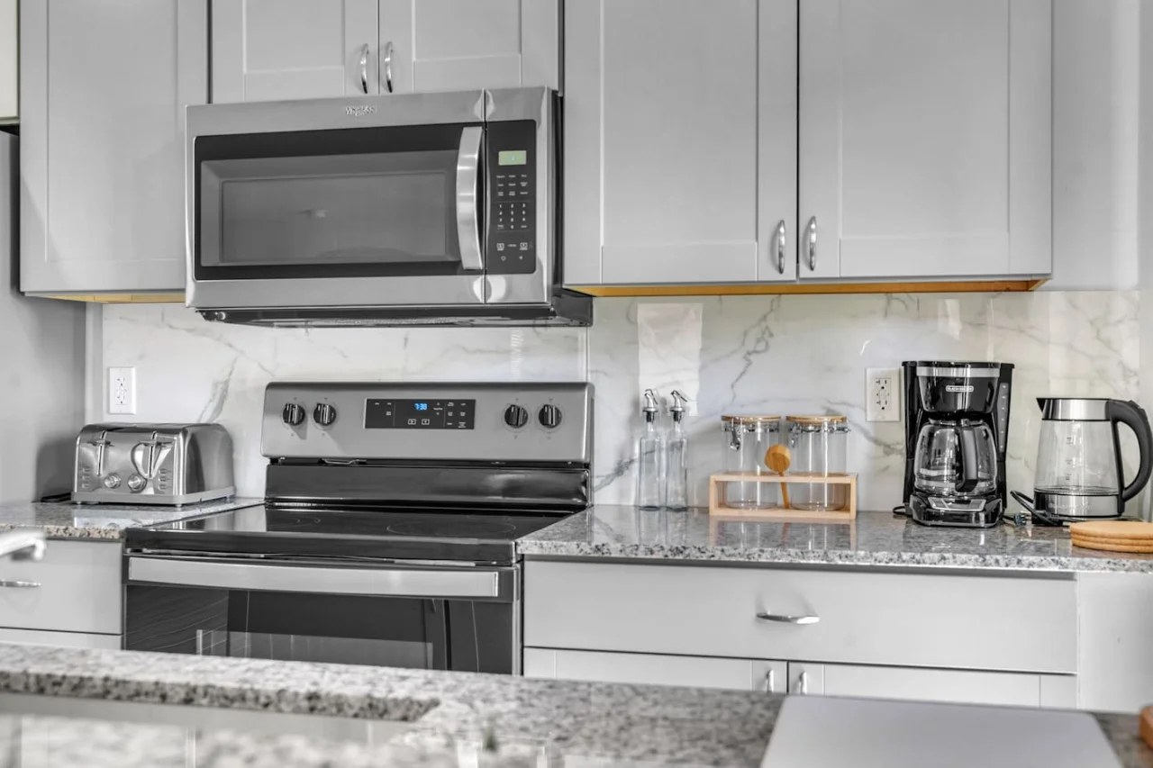 Cooking space equipped with a microwave, stove, and sleek granite surfaces for a modern culinary experience.