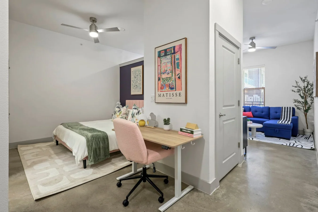 Spacious open-concept area featuring a vibrant blue sofa, modern furnishings, and a stylish entertainment setup—ideal for gatherings and relaxation.
