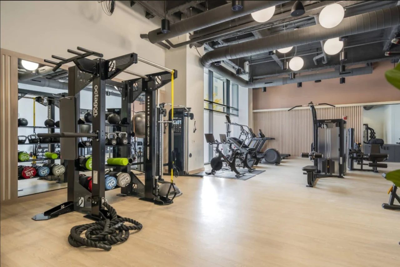 Spacious, well-lit gym equipped with a variety of cardio machines, free weights, and strength-training equipment.