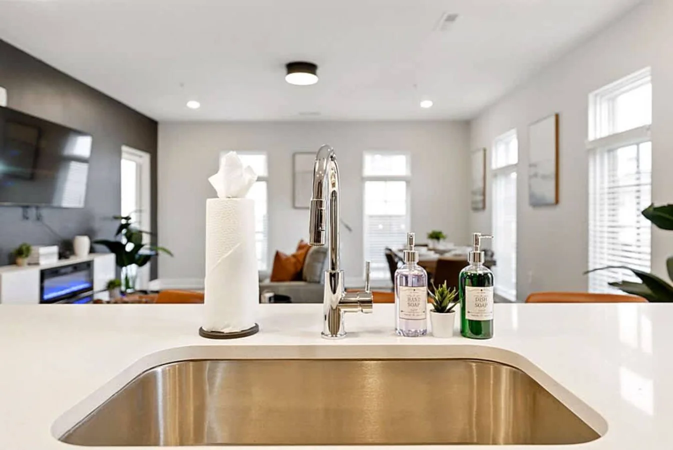 A bright kitchen view from the sink area highlighting the island, seating, and open living space. This layout makes meal prep easy while still allowing you to stay connected with guests in the adjoining rooms.