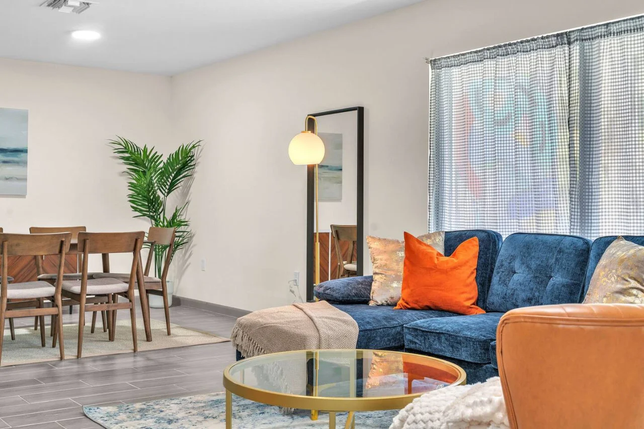 Spacious open-concept living and dining area featuring a vibrant sofa, modern furnishings, and a stylish entertainment setup—ideal for gatherings and relaxation.