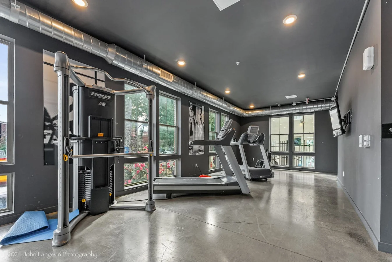 Spacious, well-lit gym equipped with a variety of cardio machines, free weights, and strength-training equipment.