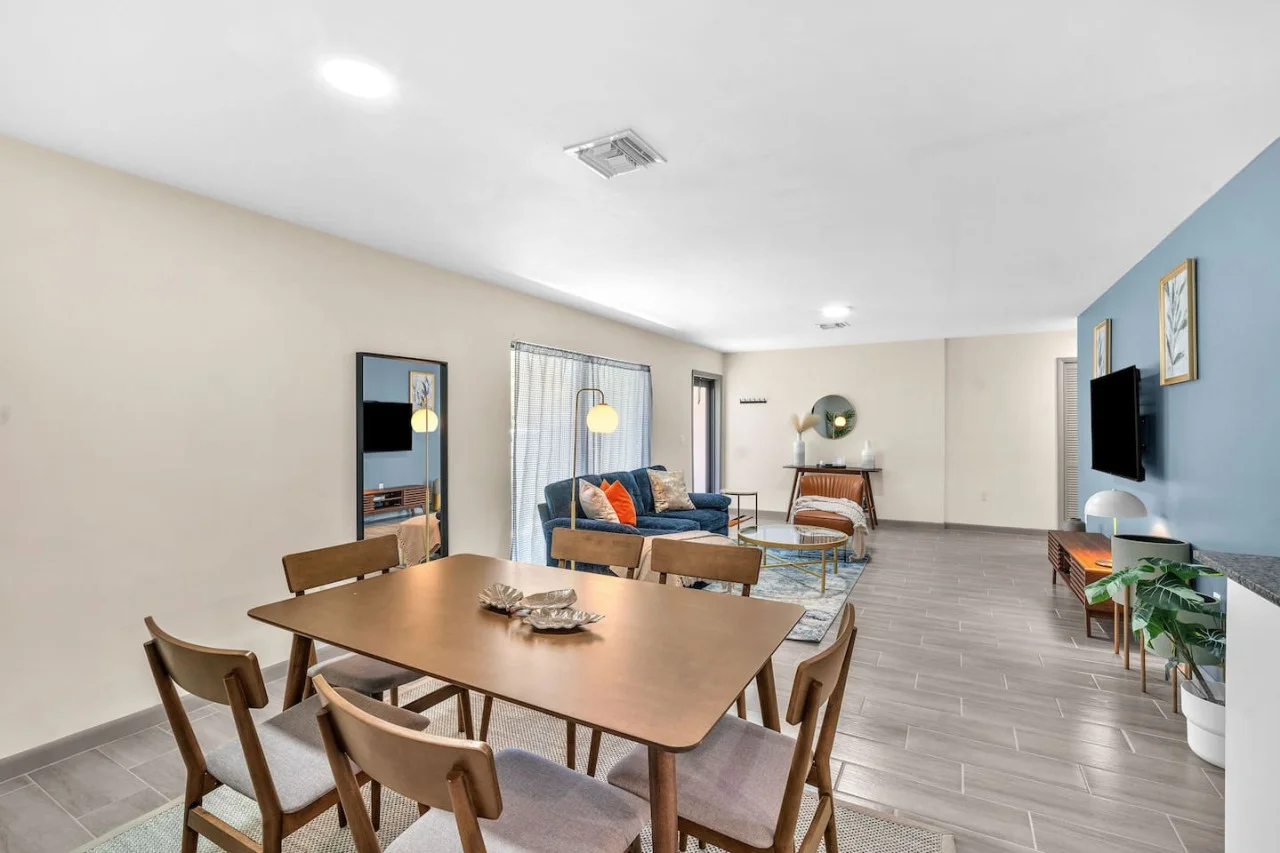 Spacious open-concept living and dining area featuring a vibrant sofa, modern furnishings, and a stylish entertainment setup—ideal for gatherings and relaxation.