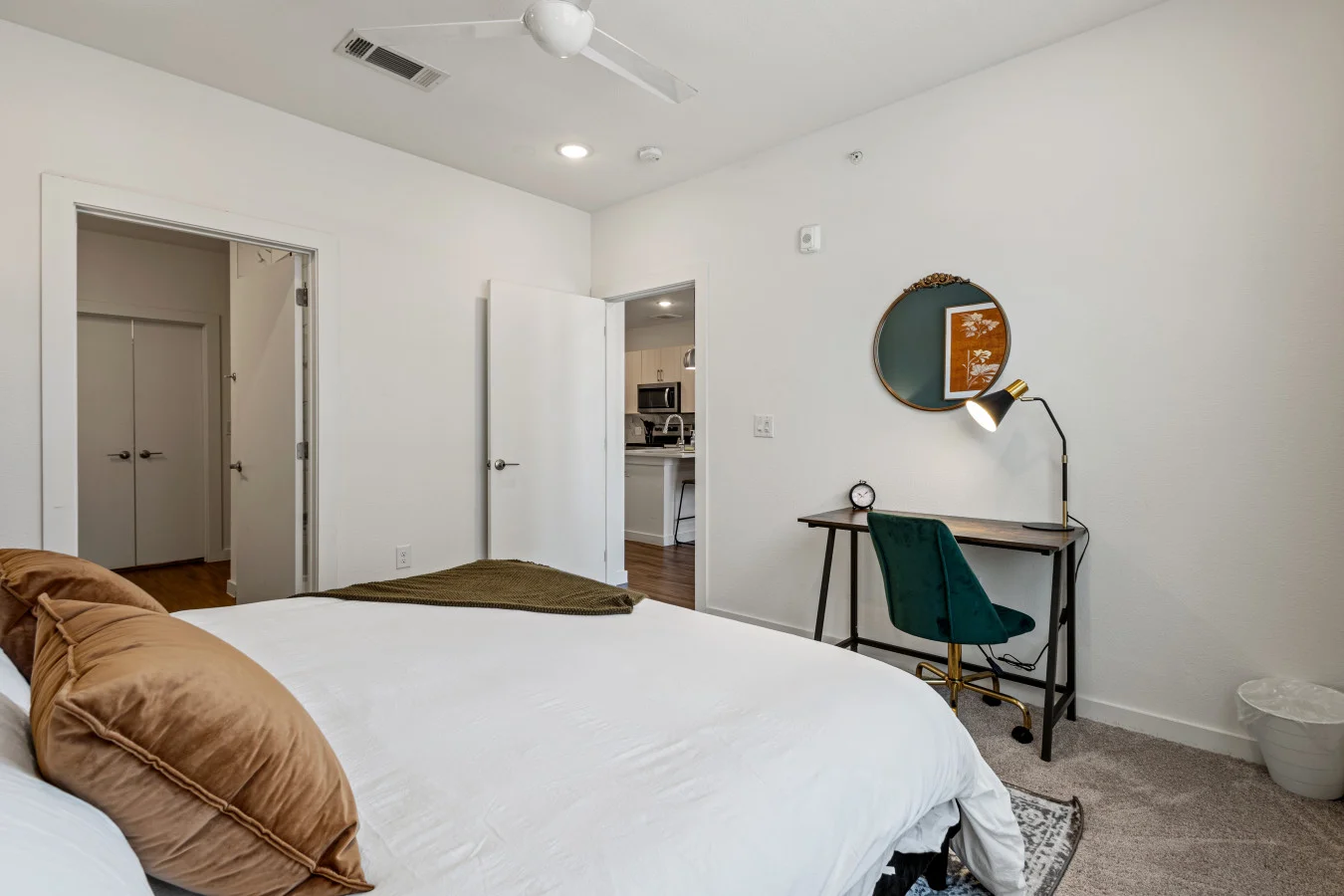 A cozy bedroom featuring a comfortable bed, dedicated workspace, and convenient access to the kitchen.
