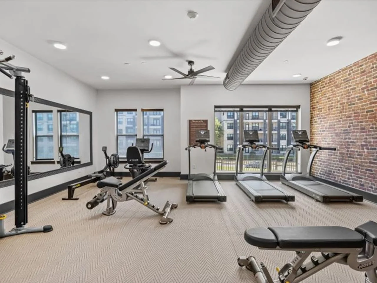 Spacious, well-lit gym equipped with a variety of cardio machines, free weights, and strength-training equipment.