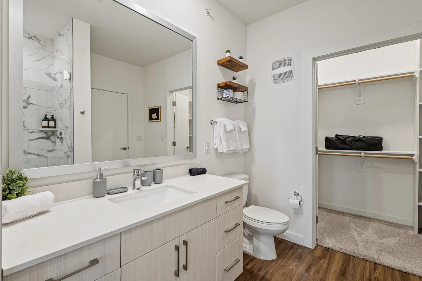Spacious modern bathroom featuring a sleek vanity, ample storage, and direct access to a walk-in closet for added convenience.