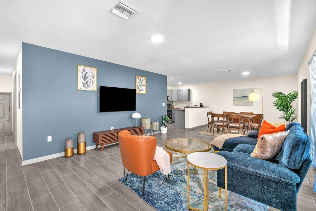 Spacious open-concept living and dining area featuring a vibrant sofa, modern furnishings, and a stylish entertainment setup—ideal for gatherings and relaxation.