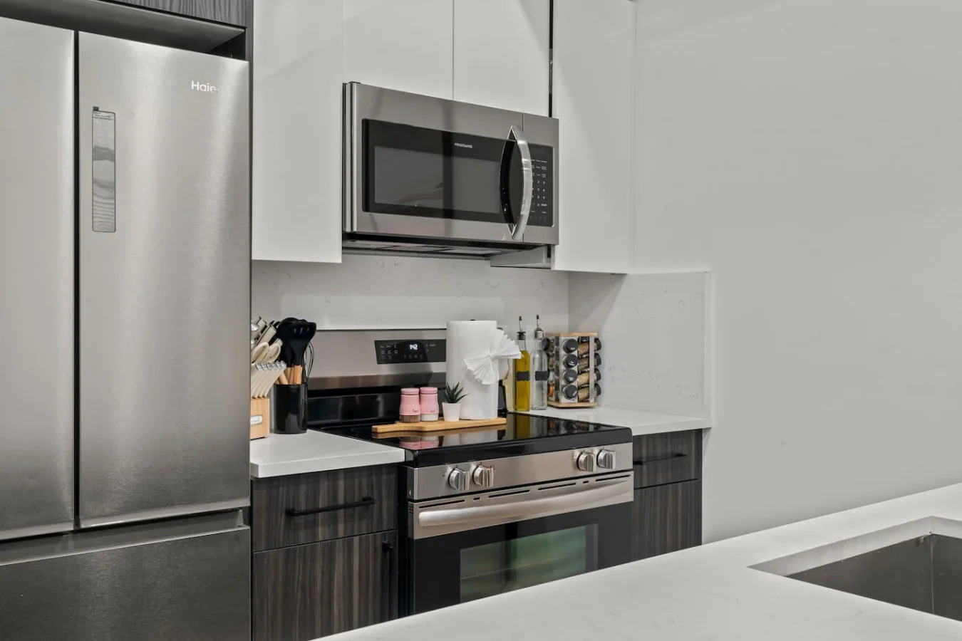 Modern kitchen with stainless steel fridge, stove, microwave, oven, utensils, knifes, spices, and more.