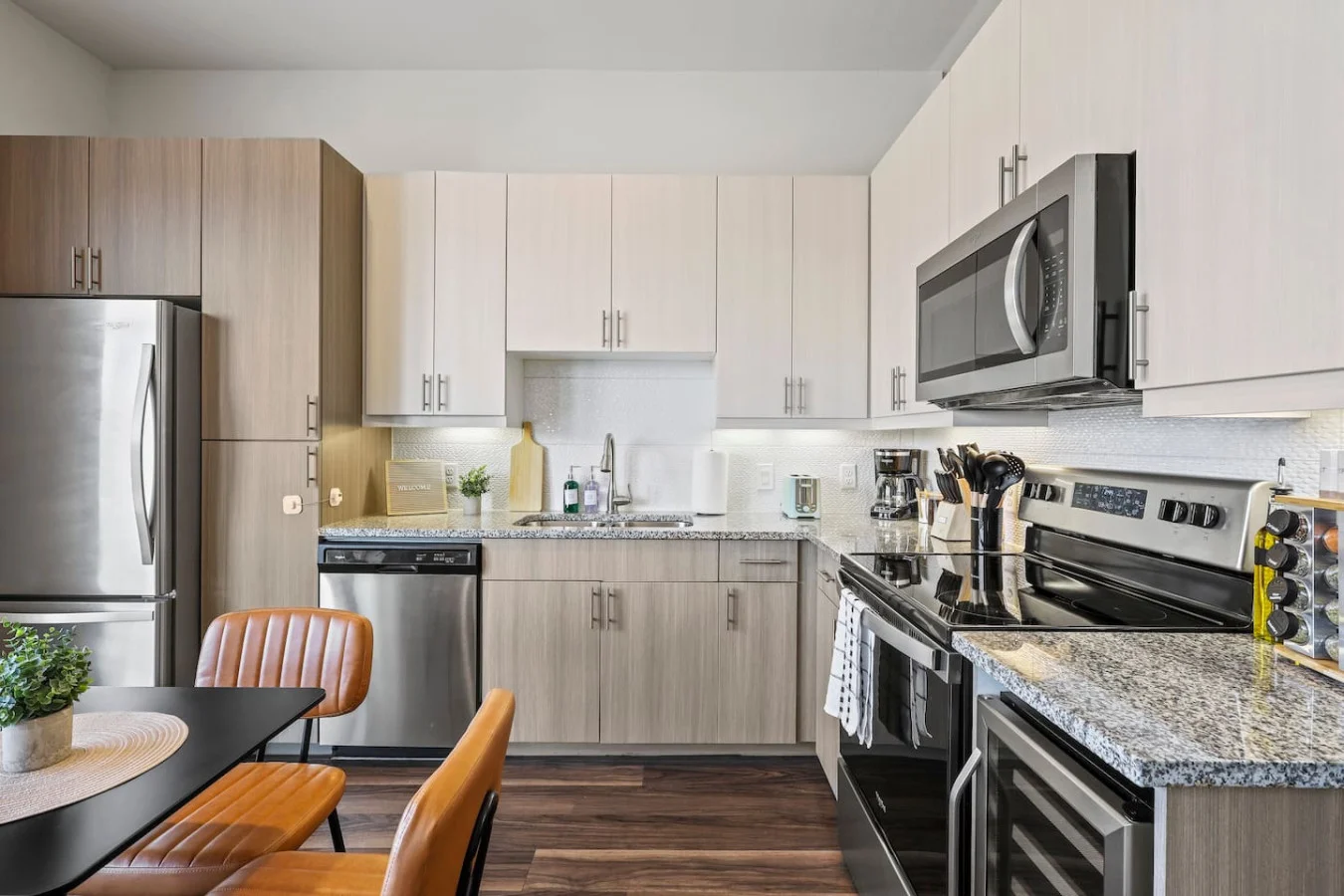 This modern kitchen features a spacious island with cabinetry, sleek white countertops, stainless steel appliances, open shelving, and stylish lighting.