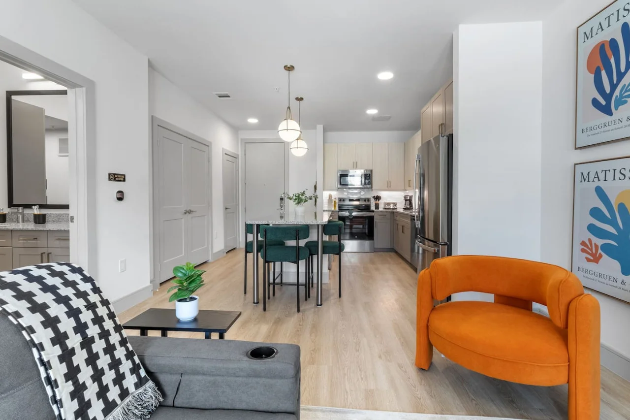 Spacious open-concept living and dining area featuring a vibrant sofa, modern furnishings, and a stylish entertainment setup—ideal for gatherings and relaxation.