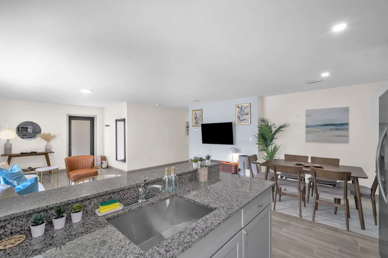 Granite countertop with a modern sink and knife set, accented by small potted plants for a sleek, functional design