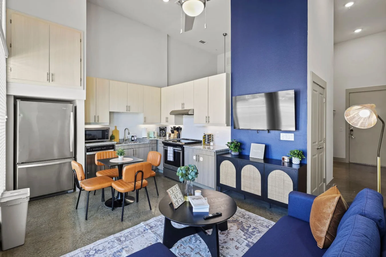 Spacious open-concept living and dining area featuring a vibrant sofa, modern furnishings, and a stylish entertainment setup—ideal for gatherings and relaxation.