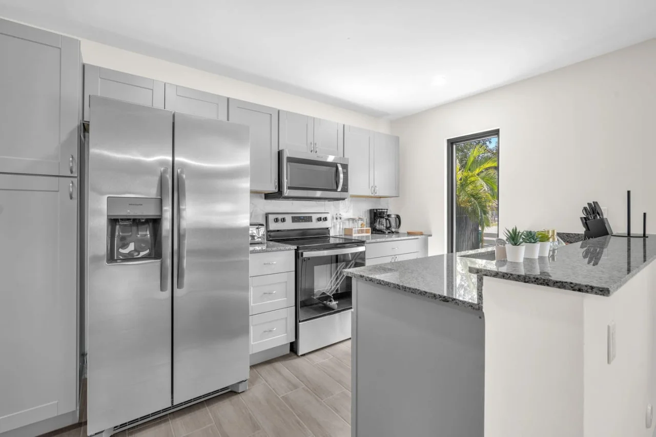 Full view of the contemporary kitchen featuring stainless steel appliances, ample storage, and bright natural lighting.