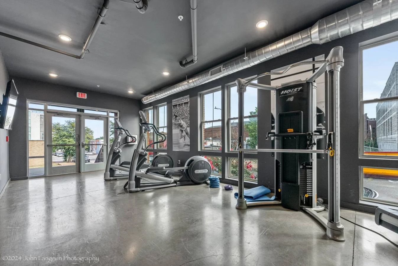 Spacious, well-lit gym equipped with a variety of cardio machines, free weights, and strength-training equipment.