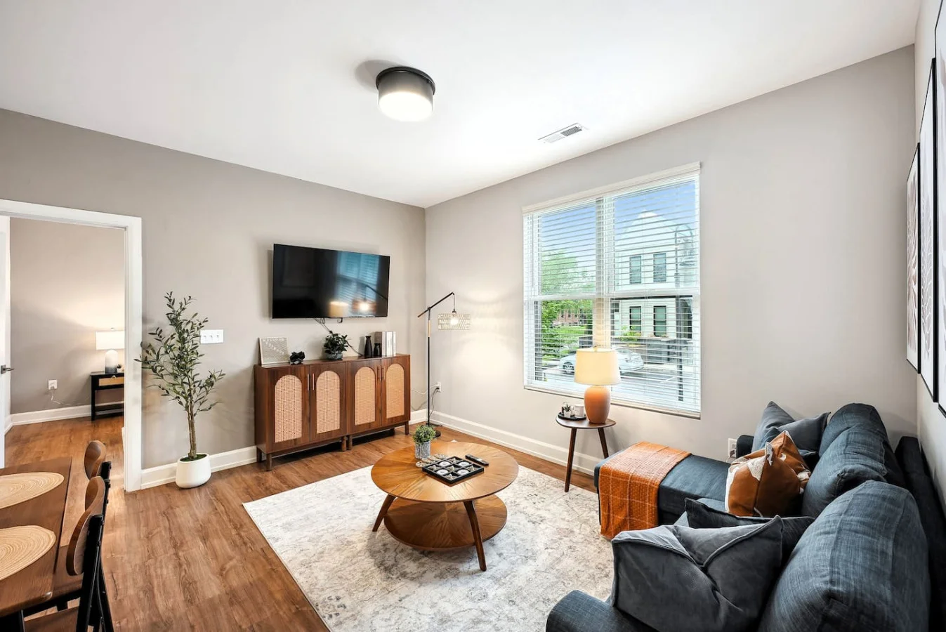 Spacious open-concept living and dining area featuring a vibrant sofa, modern furnishings, and a stylish entertainment setup—ideal for gatherings and relaxation.