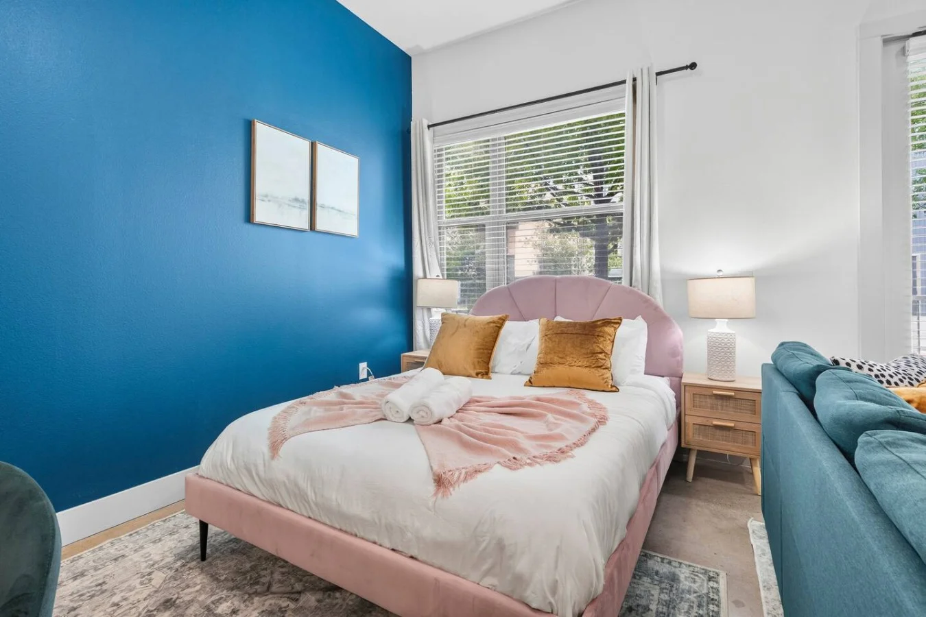 Cozy sleeping sanctuary styled with a soft pink headboard, warm mustard pillows, and vibrant wall art.