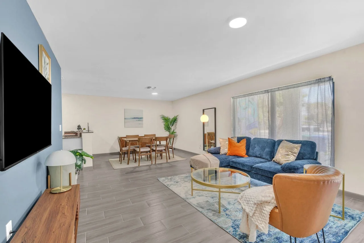 This modern living room features a bold blue and brown color scheme, a cozy sectional, a sleek TV console, stylish decor, warm lighting, and contemporary artwork.