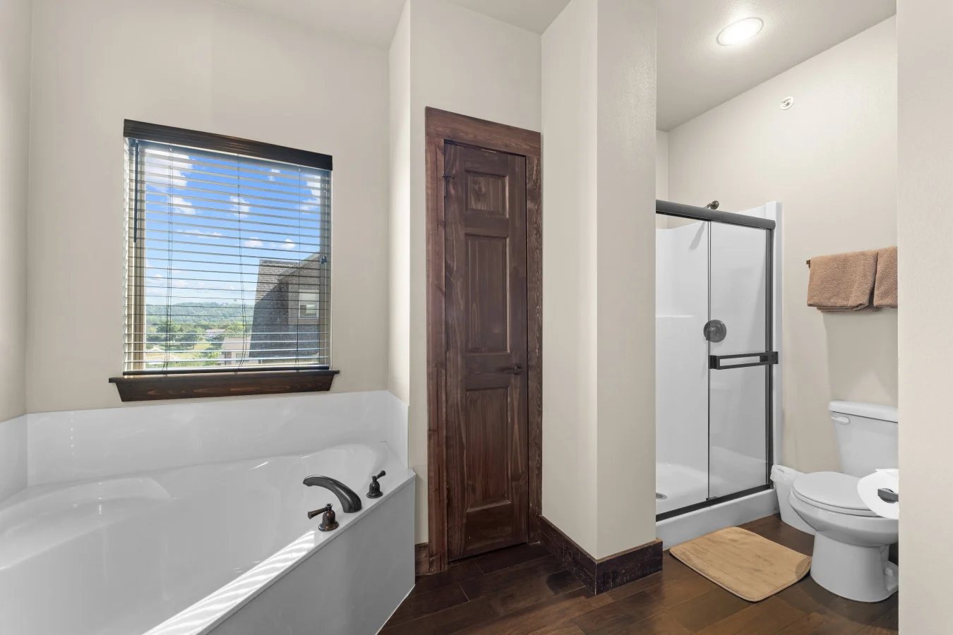 This main-floor bathroom offers a separate soaking tub and a walk-in shower, with the added convenience of a private ensuite entrance and a separate door for guest access