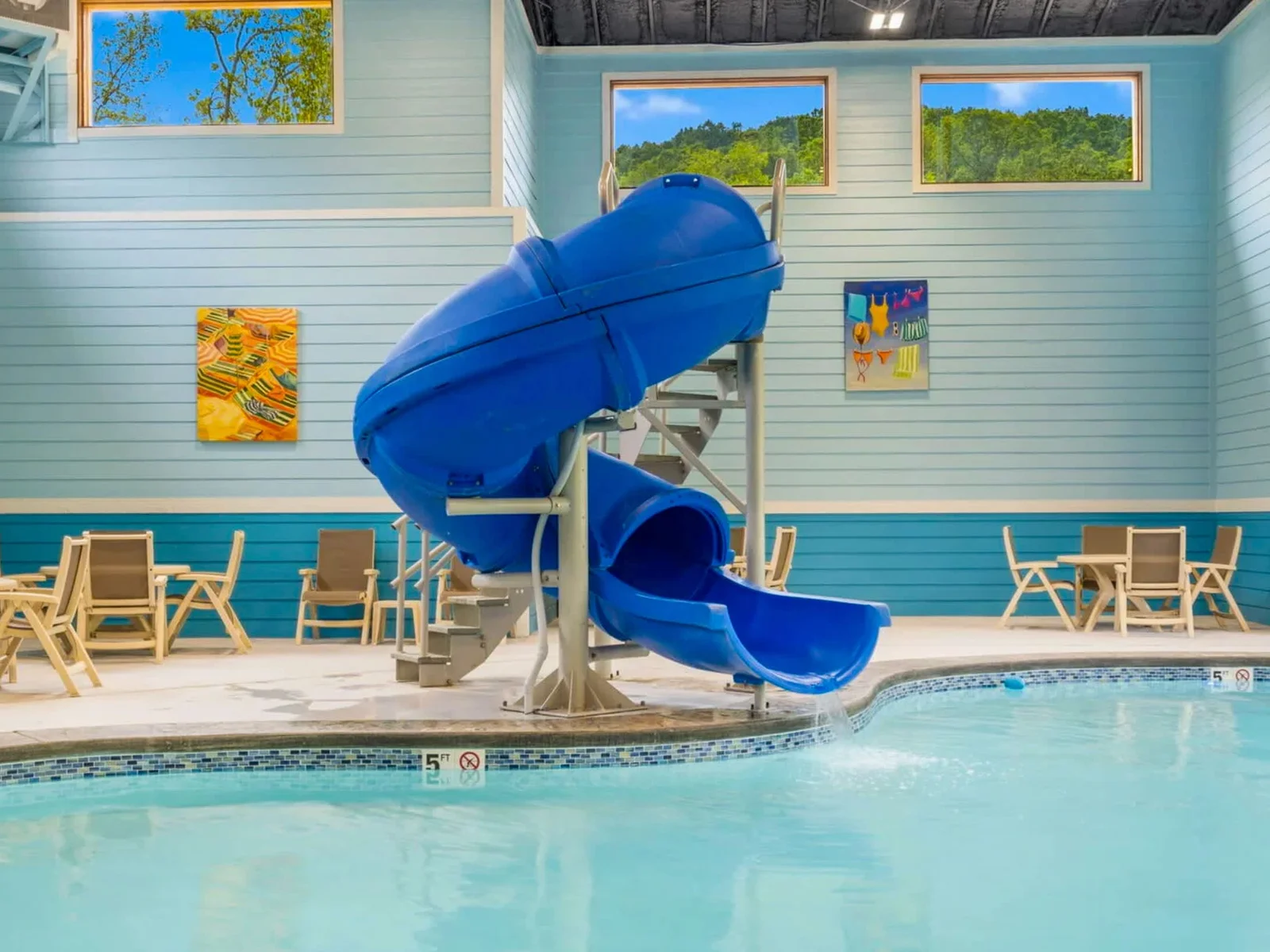 Stunning indoor pool with with slide, tables and chairs and community hot tub.