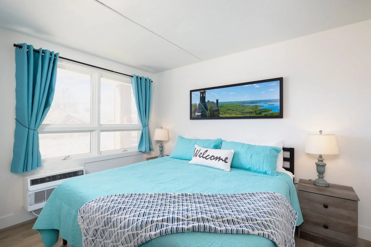 King Suite offering bedside tables with drawers and a place to hang clothes, dresser, plus luggage rack for storage.