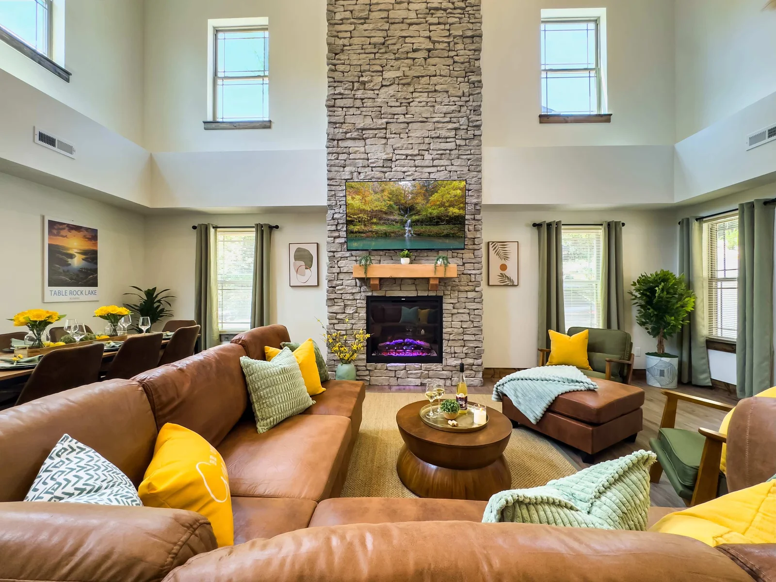 Step into the grand open-concept living area, where a soaring stone fireplace stretches toward vaulted ceilings, casting a warm, inviting glow across the richly appointed interior.