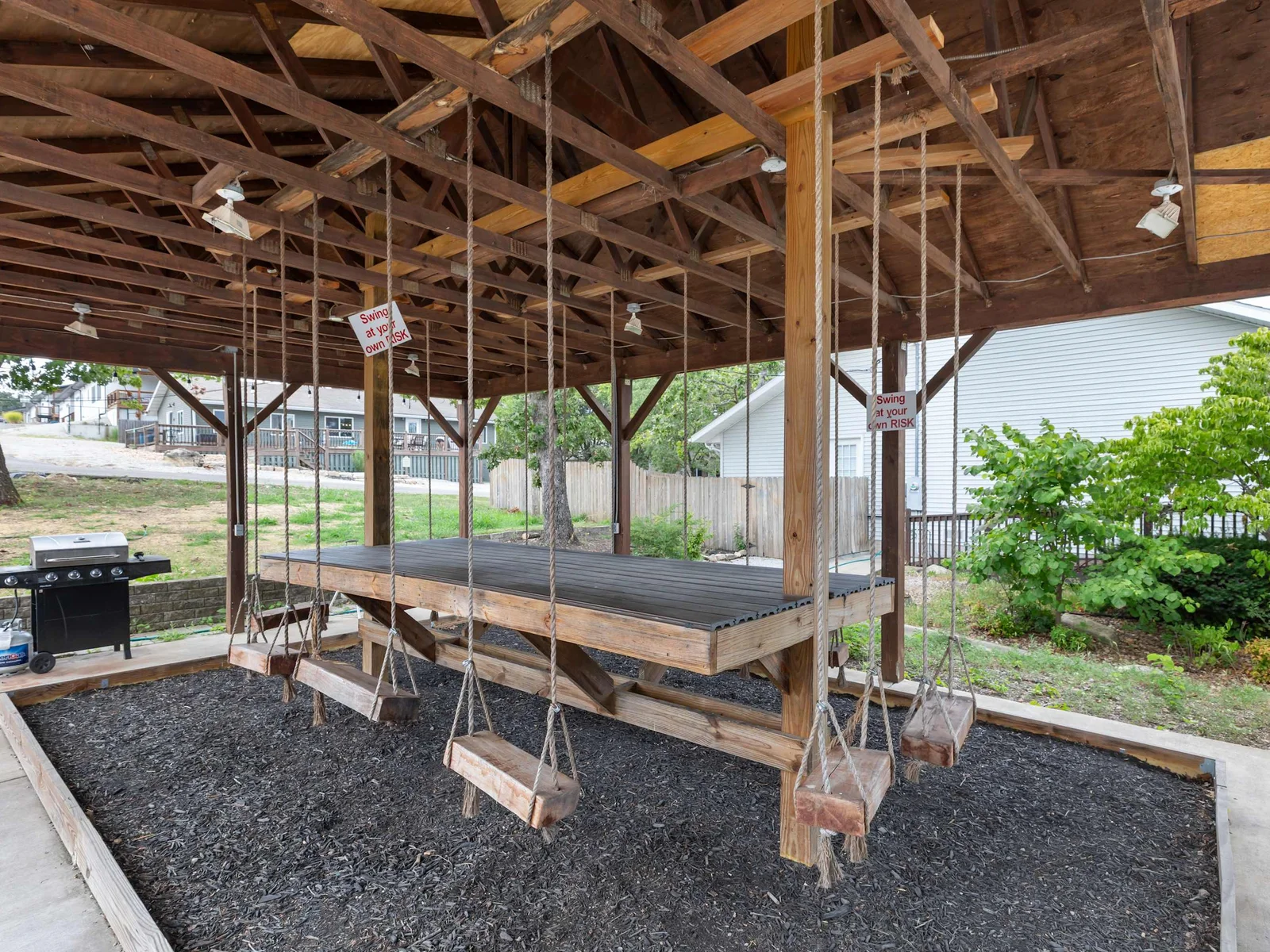 Unique shared grill area with a table and swinging chairs.