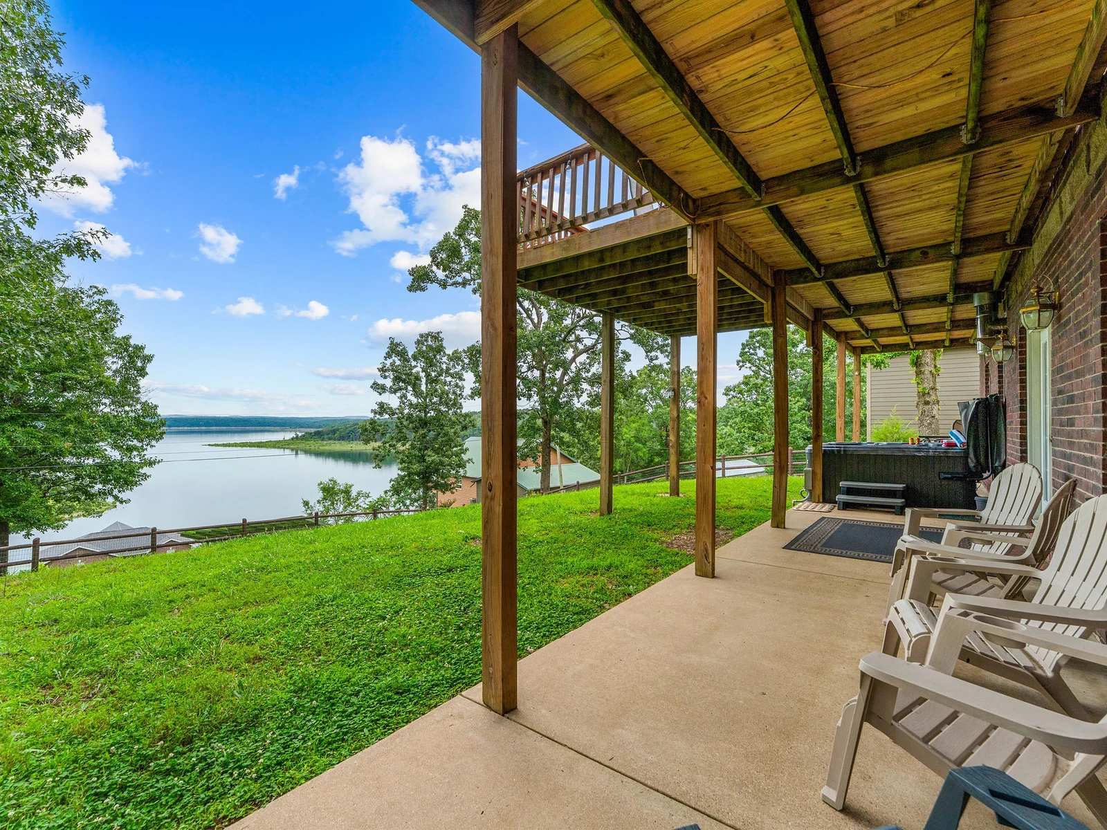 The covered lower patio connects the hot tub to the lawn, looks straight out at the lake, and stays shaded all afternoon. A quieter spot than the upper deck when you want it.