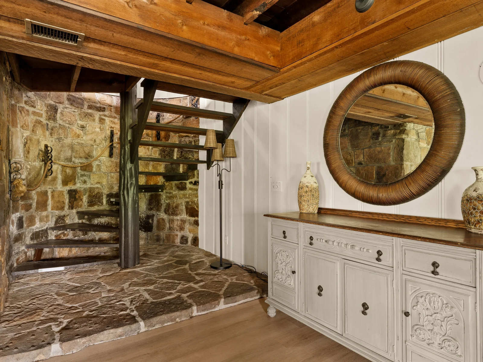 A beautifully layered space where rustic stone meets warm wood—right beneath the spiral staircase.