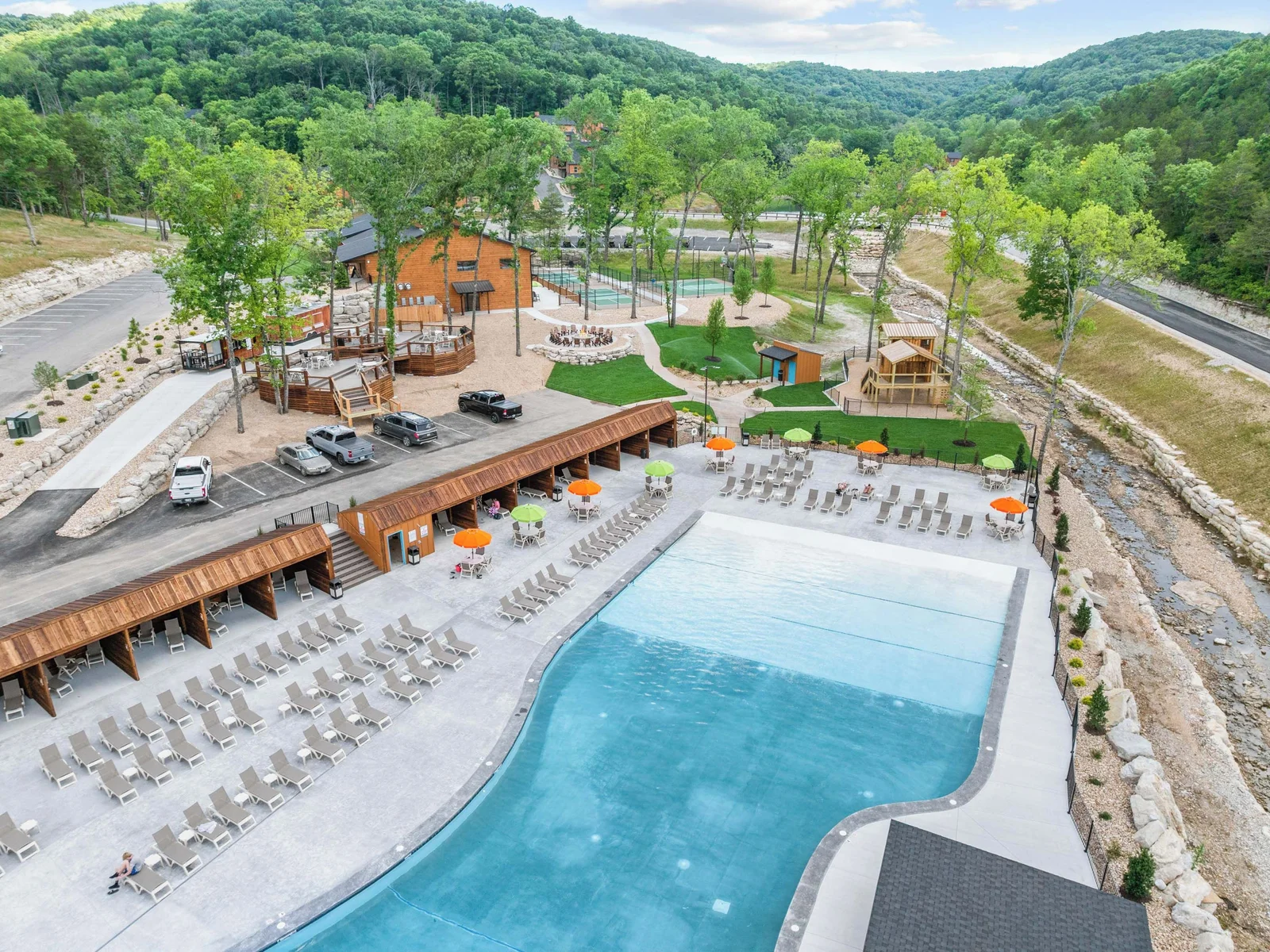 Outdoor pool with view of playground, outdoor community firepit and chairs.