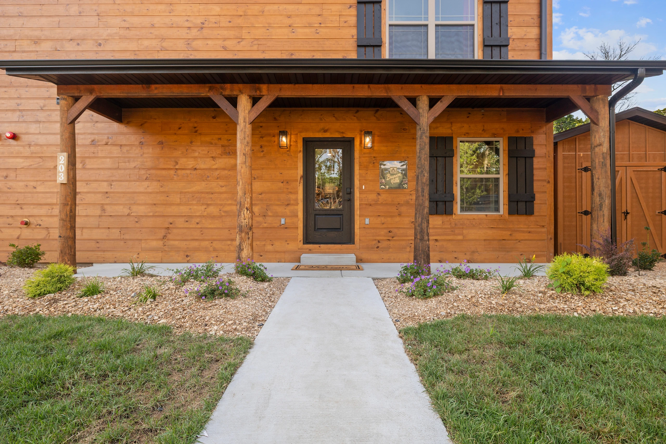 Timber posts frame the covered front porch and the walk up to the door.