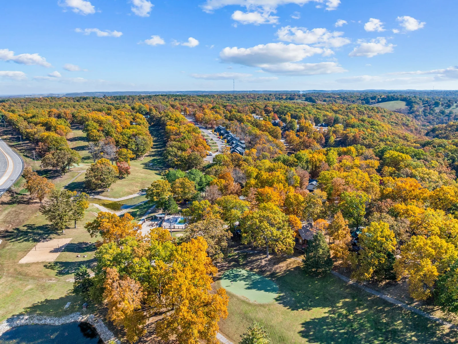 Aerial of the neighborhood with shared pool and putting green. Wooded trails, open lawns and fall color in every direction.