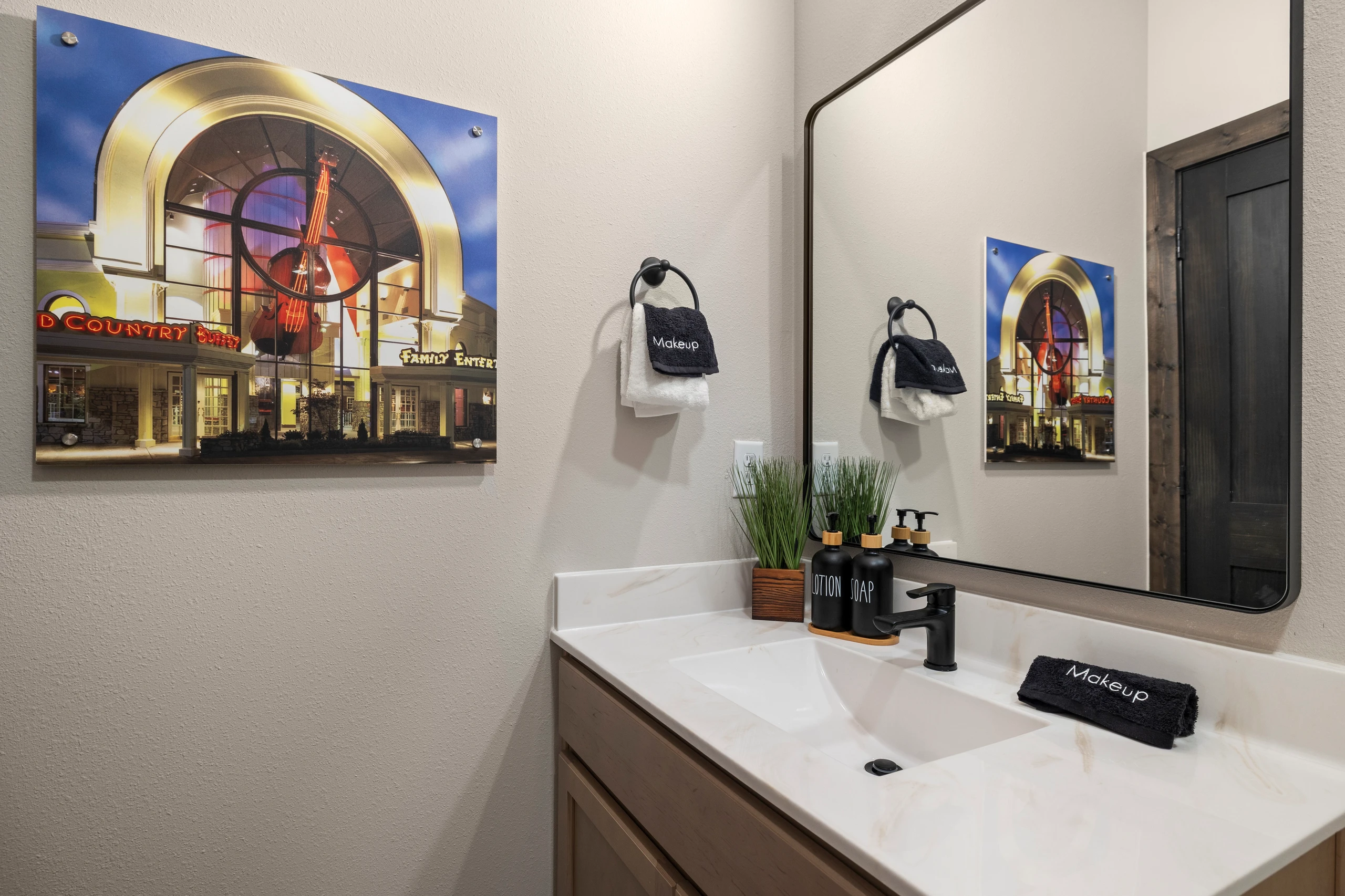 Framed theater art hangs over a black-fixture vanity.