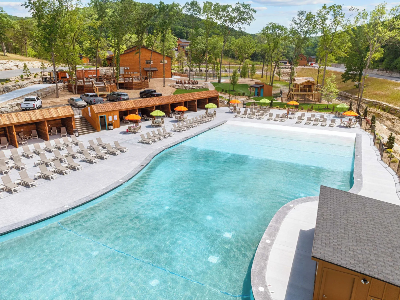 Outdoor pool with view of playground, outdoor community firepit and chairs.