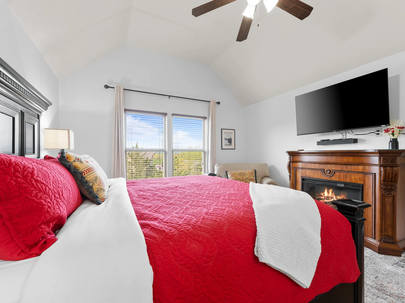 Luxurious bedroom with sturdy furniture, an electric fireplace, TV and ensuite bathroom.