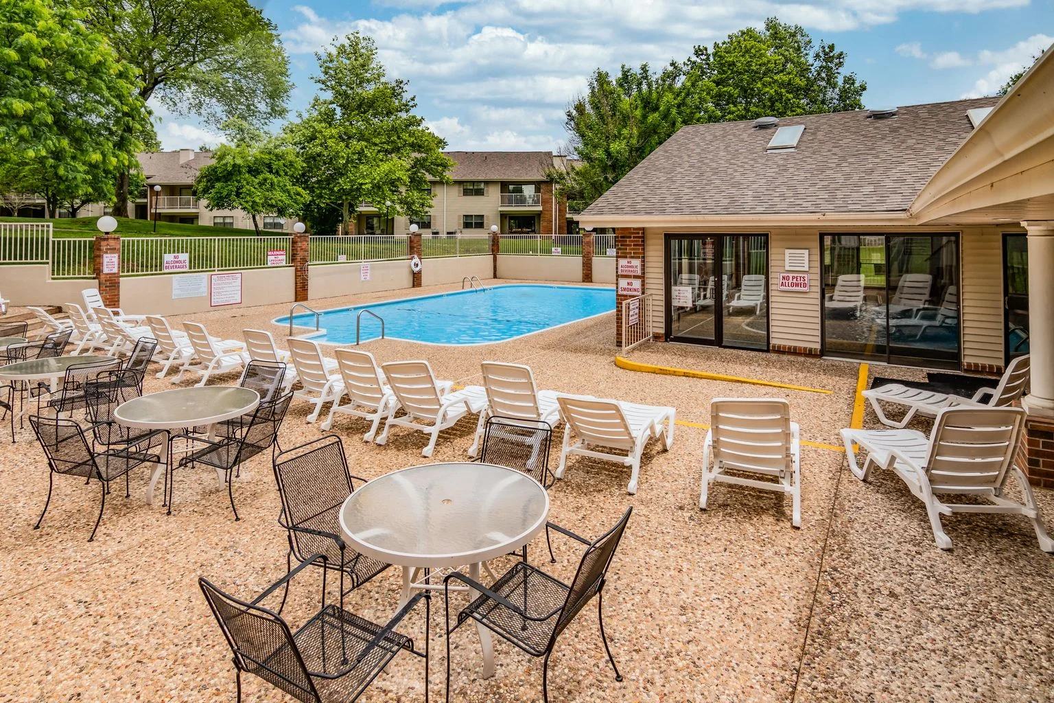 Resort-style outdoor pool with lounge seating and tables.