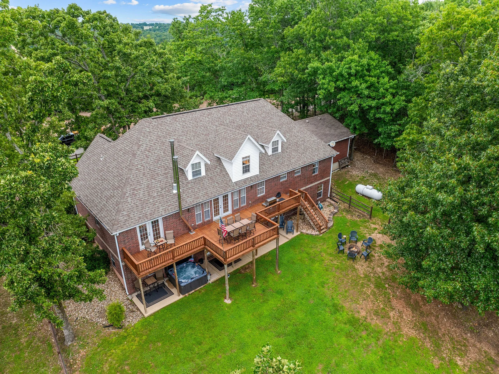 From above you can see the full footprint: three levels, multiple decks, a lower patio with hot tub, and the fire pit lawn all tucked into the trees. That is 3,986 sq ft of retreat.