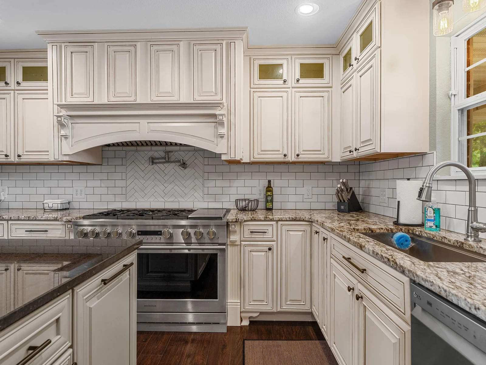 The 6-burner pro range and custom hood, surrounded by herringbone subway tile all the way to the ceiling — this is not a vacation rental kitchen. This is a real one.